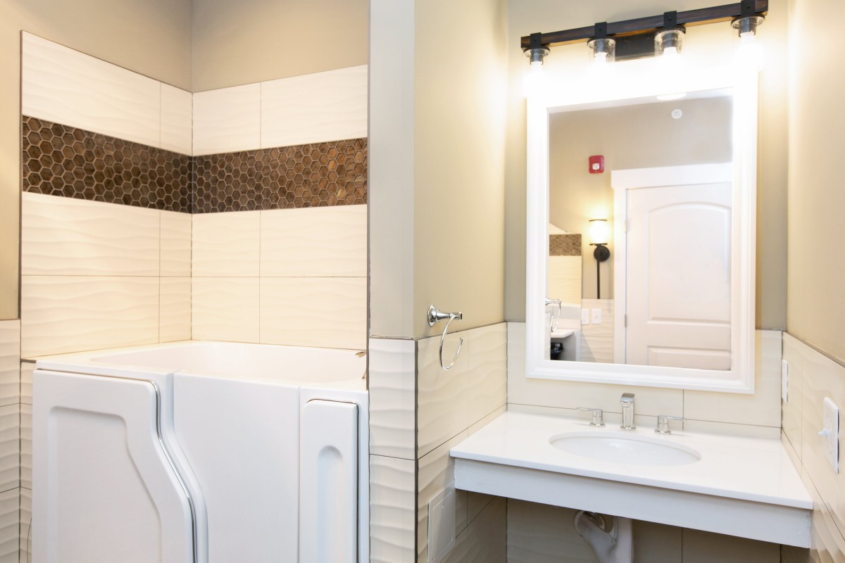 A modern bathroom with a washing machine and well-lit mirror.