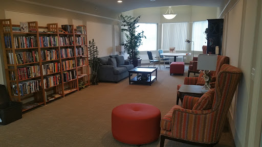 A cozy lounge area with a bookshelf, comfortable seating, and indoor plants, perfect for relaxation or reading.