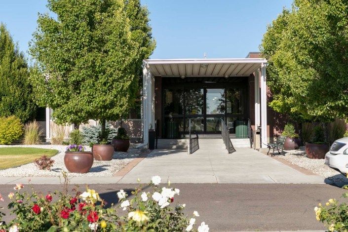 A modern building entrance with a landscaped pathway and potted plants.