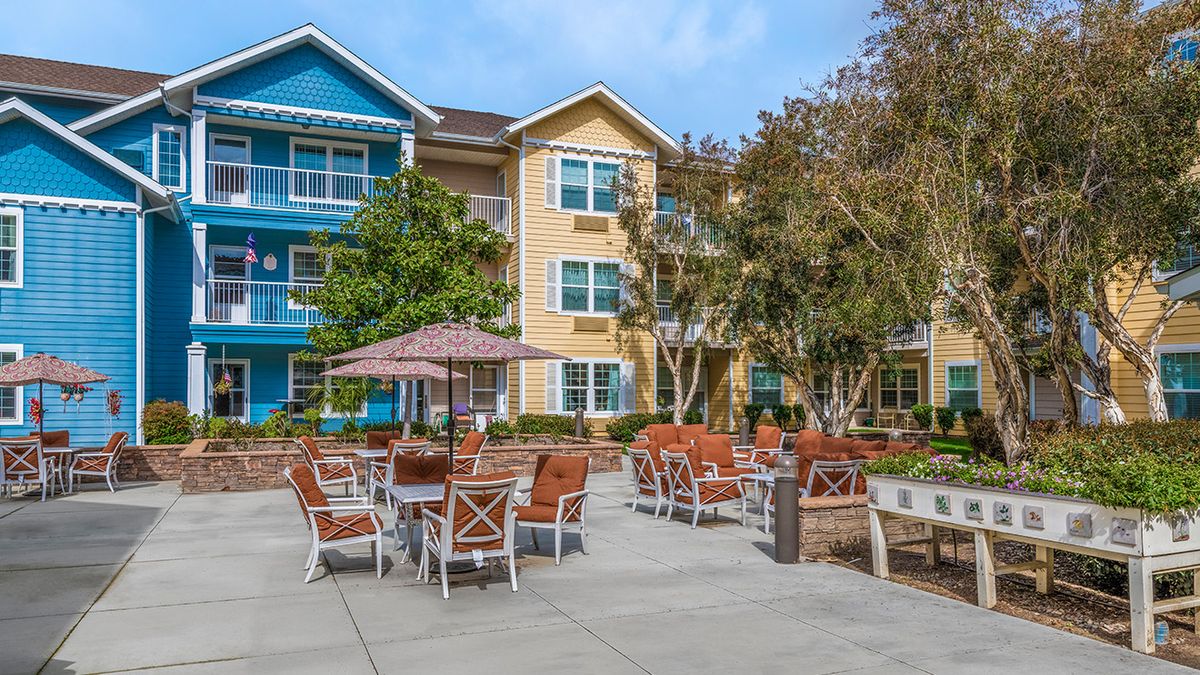 A colorful apartment building with outdoor seating and umbrellas in a residential area.