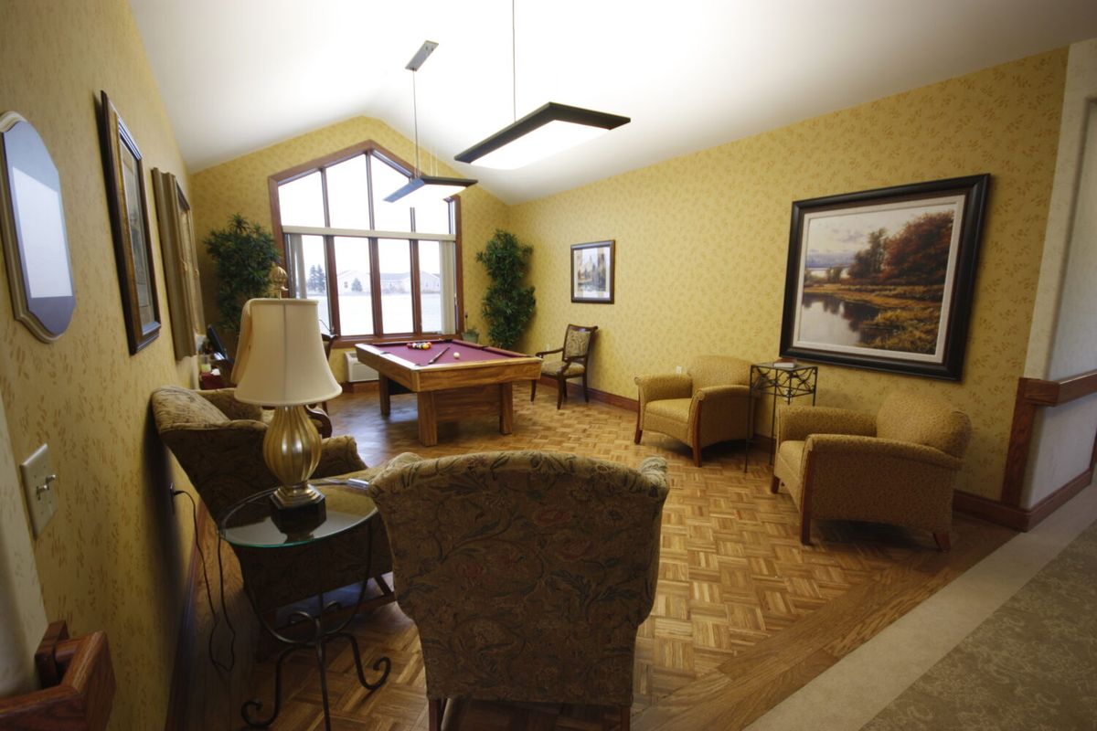 A cozy living room featuring a pool table, armchairs, and vibrant artwork.