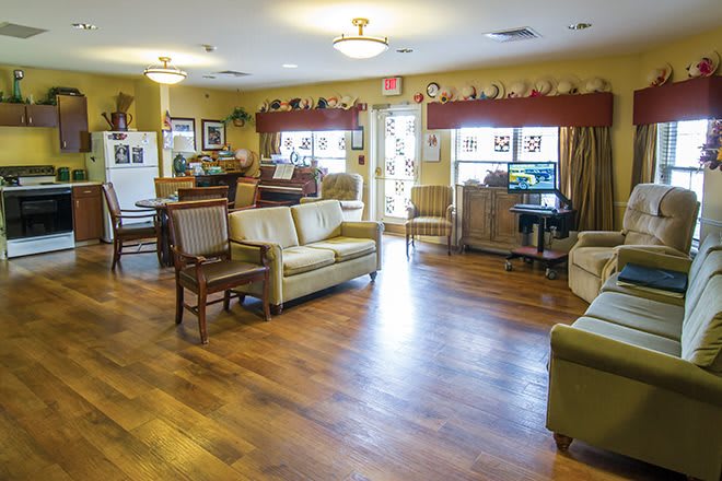 A cozy living room with sofas, chairs, and wooden flooring, creating a warm and inviting atmosphere.