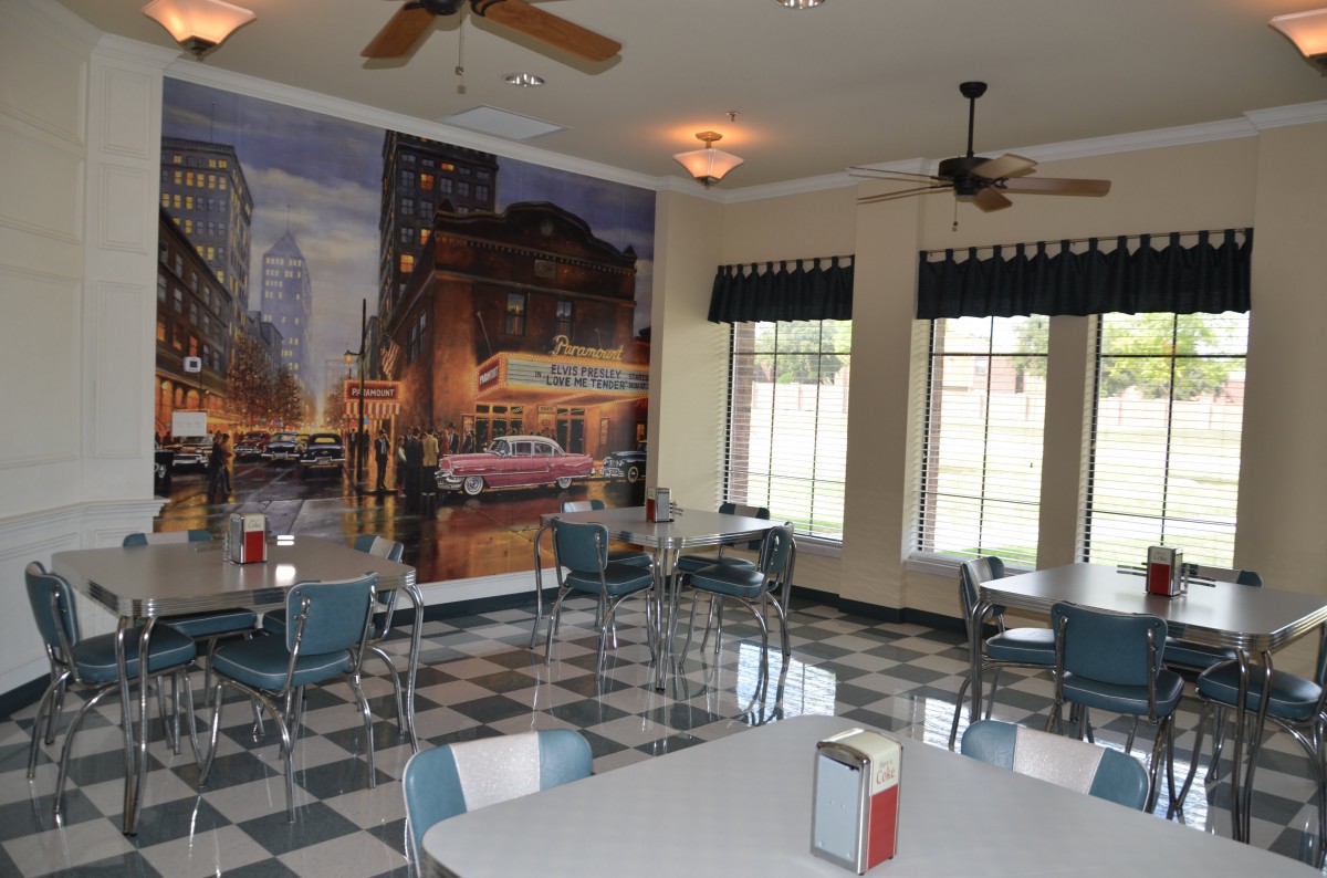 A retro-themed diner interior with checkered flooring, vintage decor, and a cityscape mural on the wall.