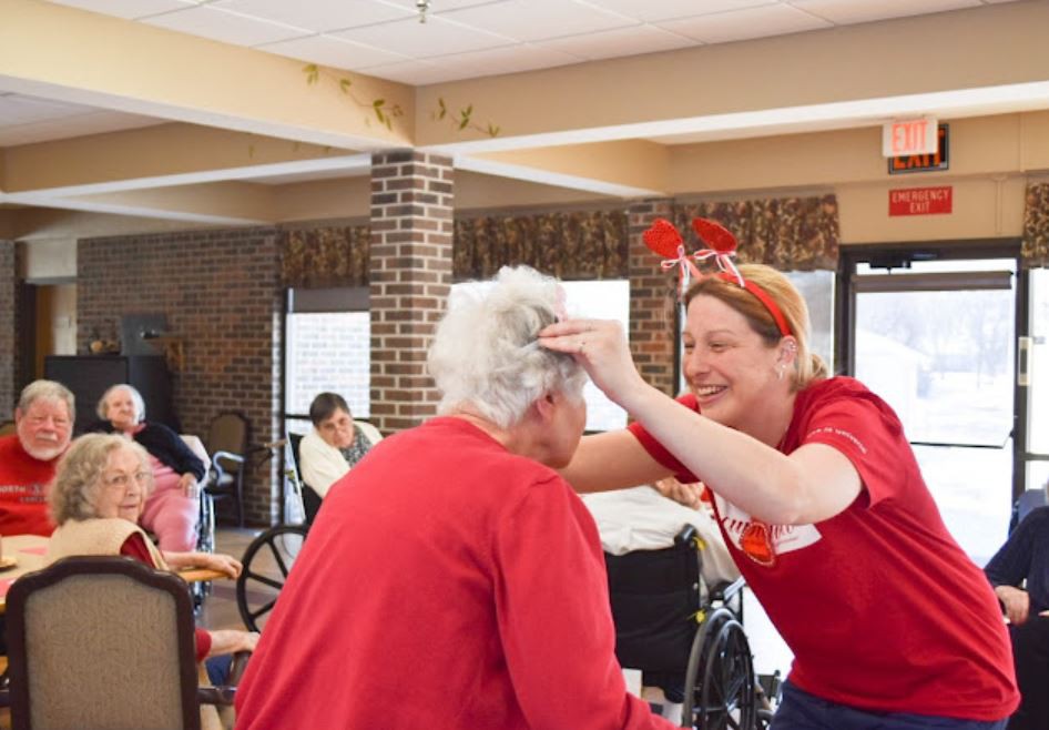 A caregiver playfully interacts with a senior resident, sharing a joyful moment together.