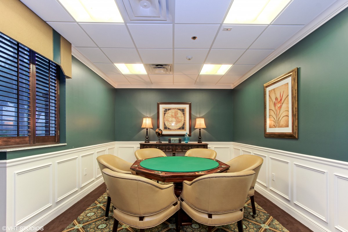 A cozy game room featuring a poker table and chairs, with elegant artwork adorning the walls.