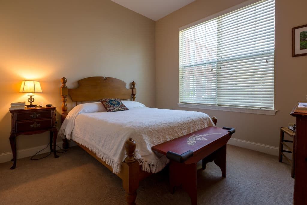A cozy bedroom with a large bed and natural light filtering through the window.