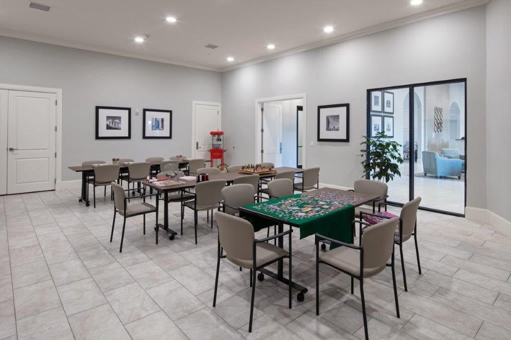 A well-lit meeting room with multiple tables and chairs, a popcorn machine, and framed photos on the walls.