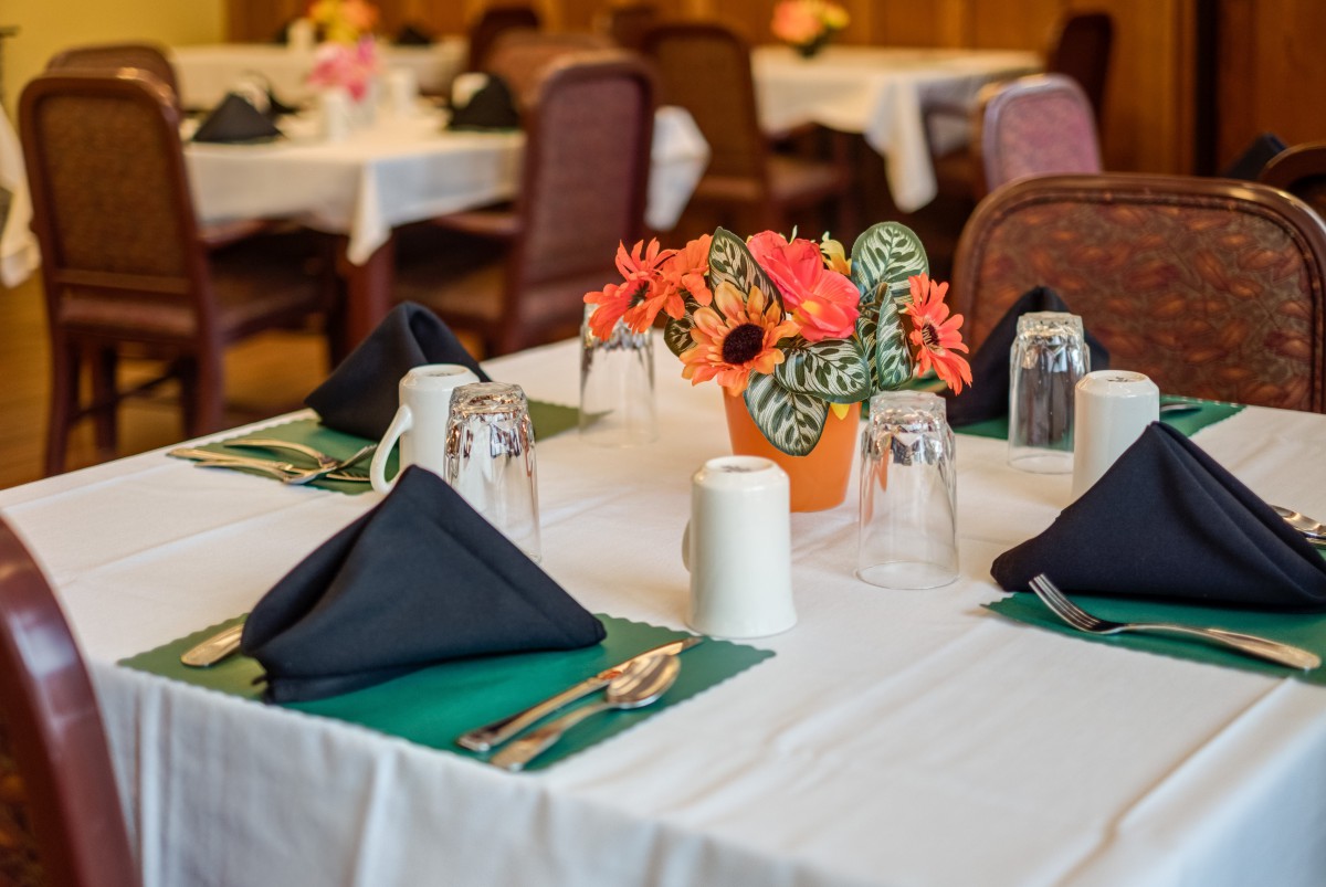 A neatly arranged dining table with floral centerpiece and place settings.