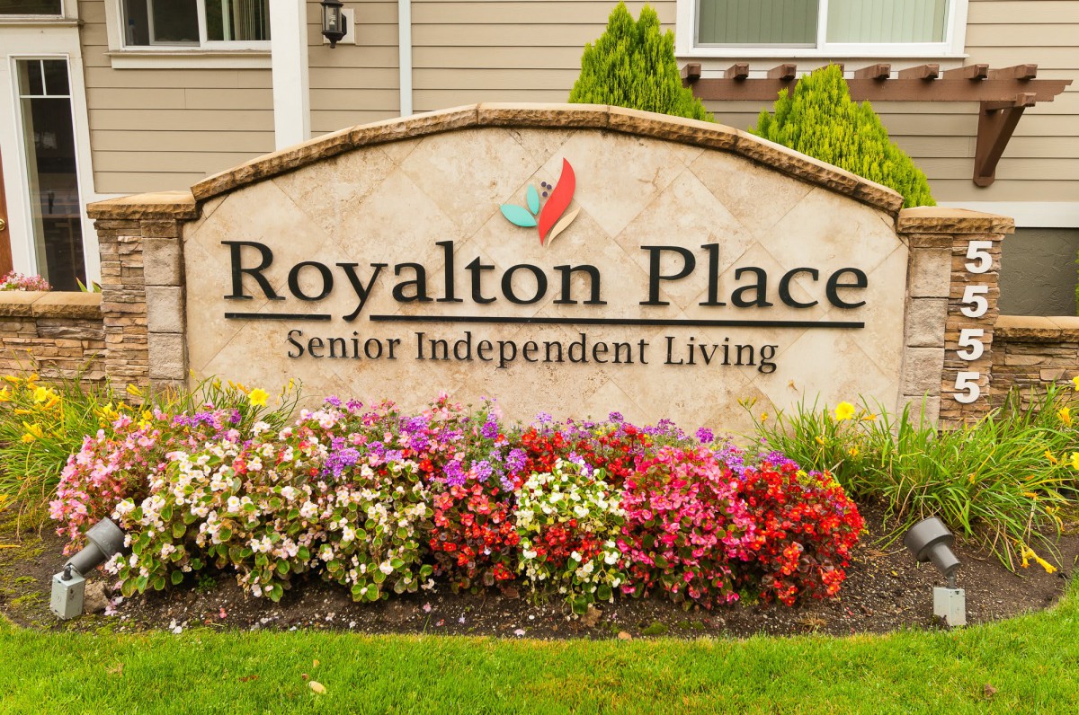Sign for Royalton Place Senior Independent Living with colorful flowers in front.