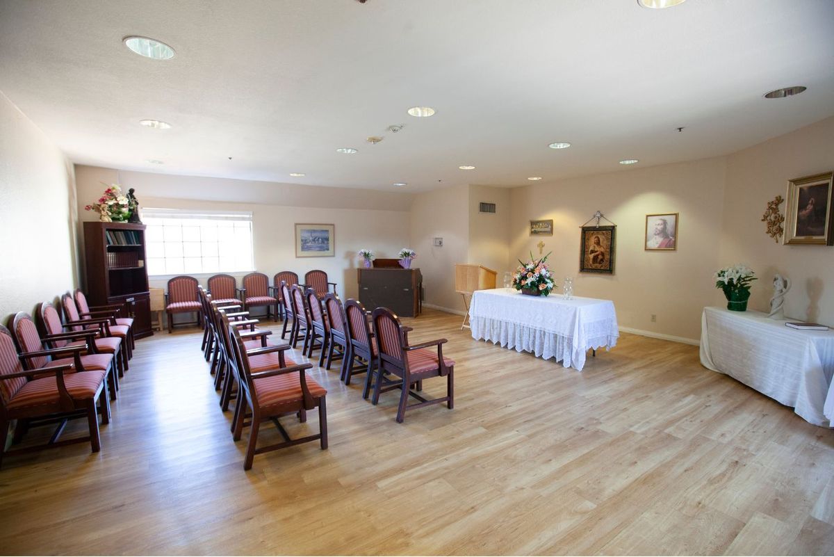 An empty chapel room arranged for a small ceremony with rows of chairs.