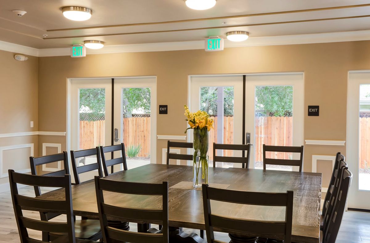 A cozy dining room with a wooden table and chairs, adorned with a vase of flowers.