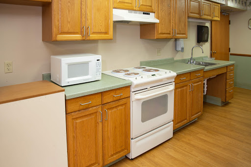 A tidy kitchen featuring a microwave, stove, and wooden cabinets.