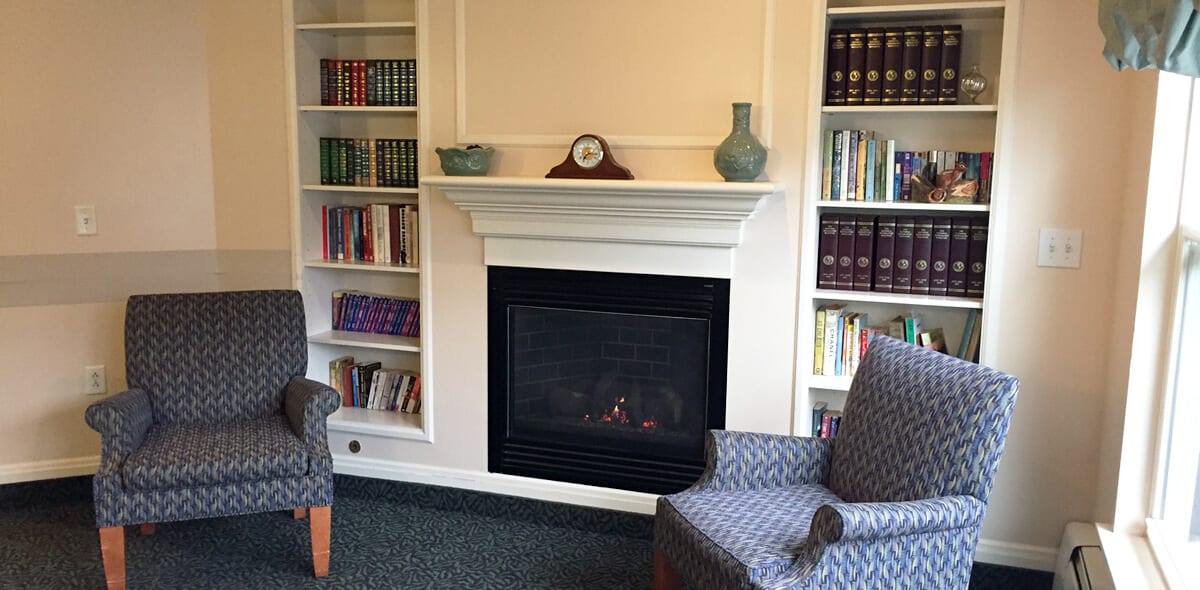 A cozy living room with a fireplace flanked by bookshelves and armchairs.
