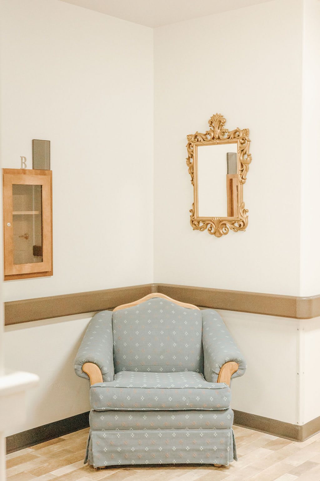 A cozy corner featuring an elegant armchair and a decorative mirror on the wall.