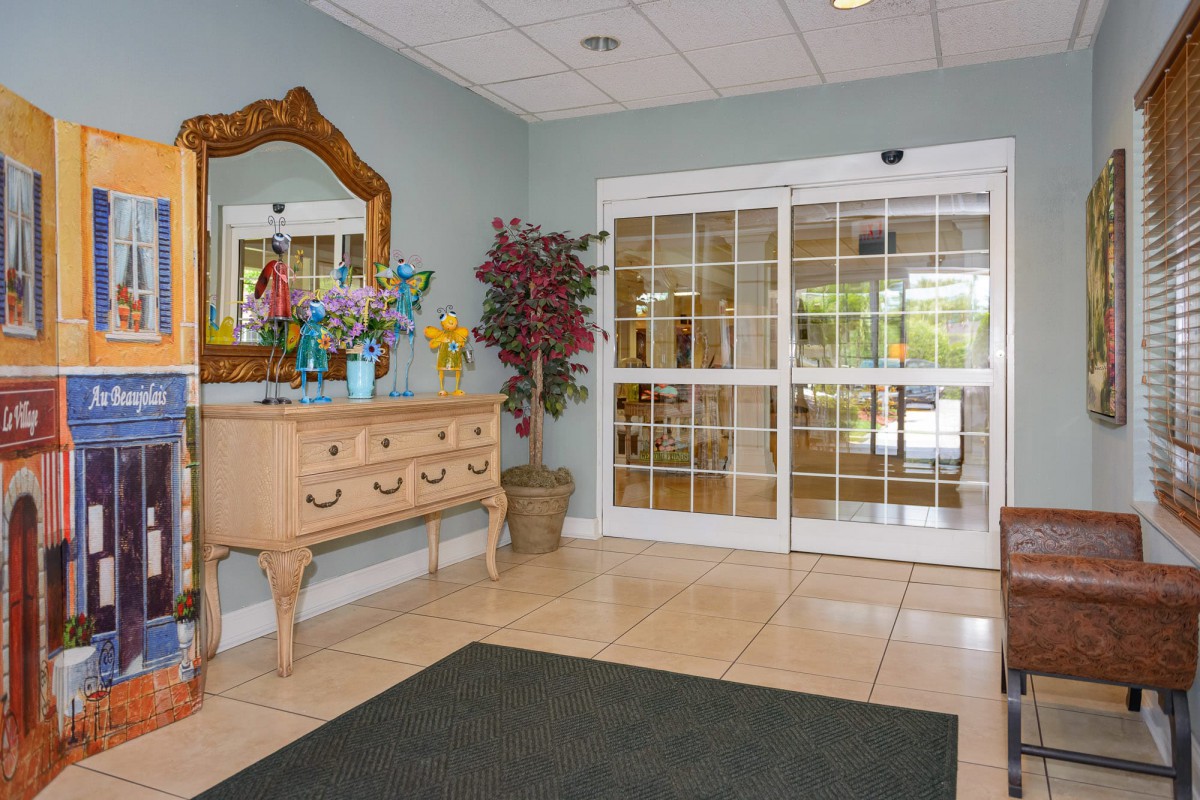 A welcoming lobby with a decorative table and mirror beside glass entrance doors.