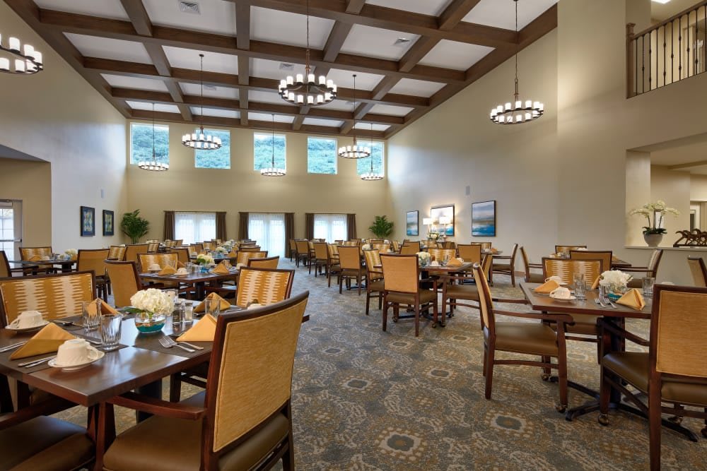 Spacious modern dining area with elegant chandeliers and neatly arranged tables and chairs.