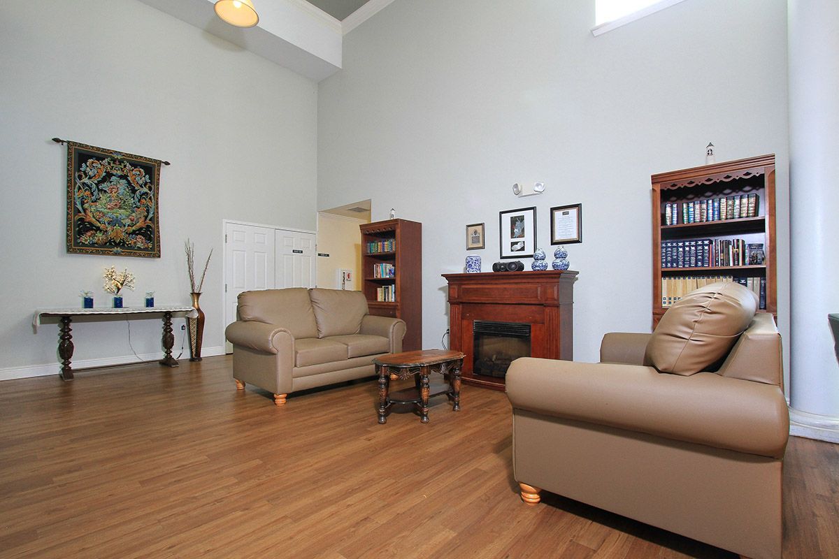 A cozy living room with sofas, a fireplace, bookshelves, and wooden flooring.