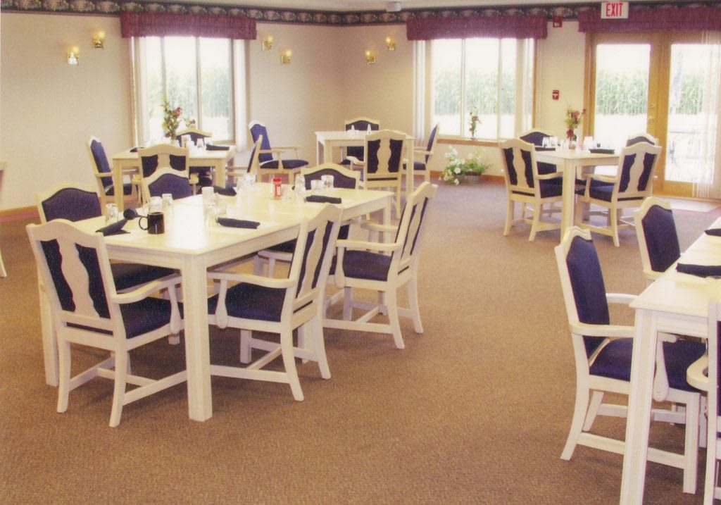 A spacious dining room with multiple tables and chairs, surrounded by large windows.