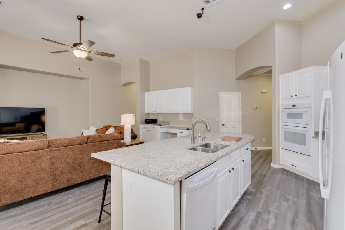 Modern open-plan kitchen and living area with neutral tones and a ceiling fan.