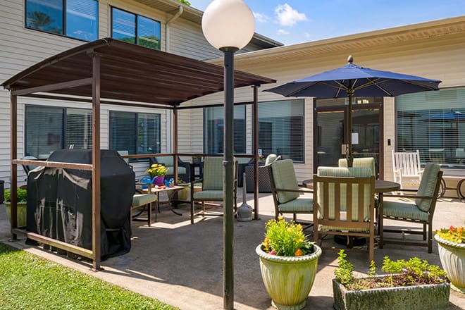 A cozy outdoor patio area with furniture, a grill, and potted plants under a clear blue sky.