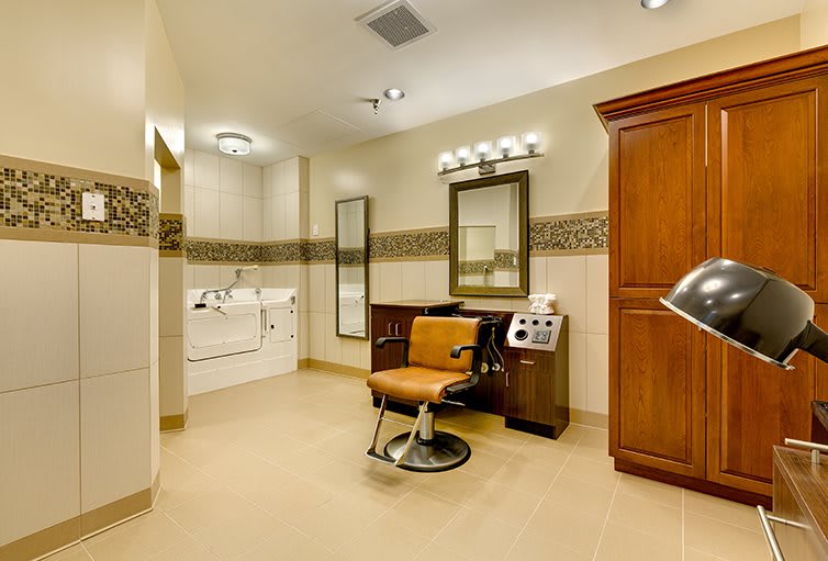 A modern salon interior featuring a barber chair, mirror, and ample lighting.