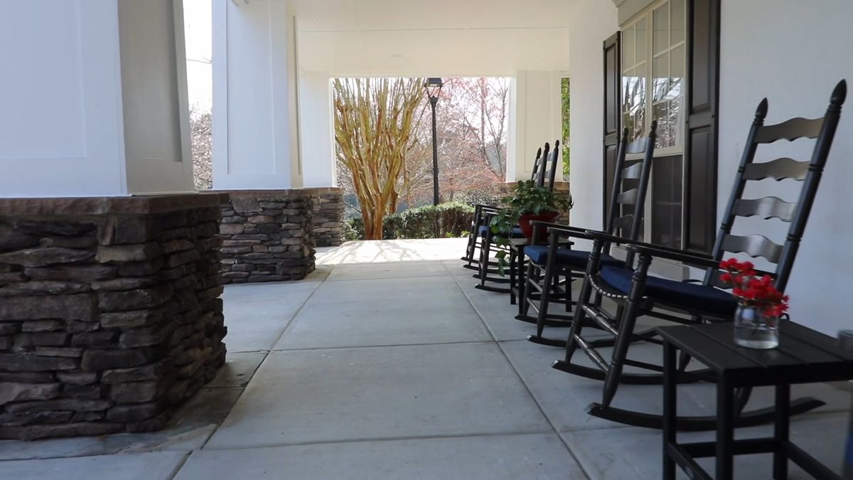 A row of rocking chairs lined up on a porch with columns, offering a peaceful outdoor seating area.