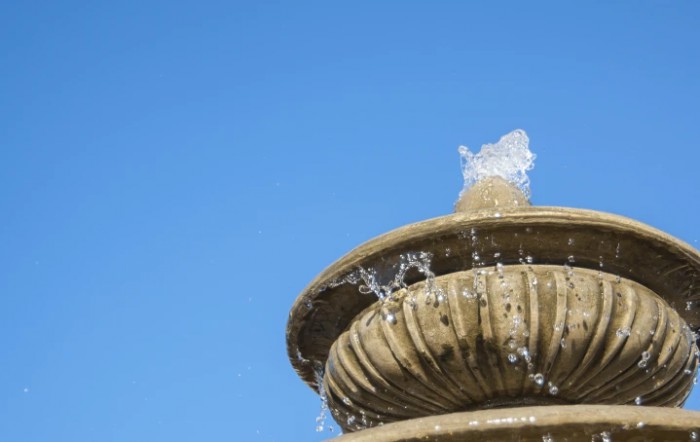 Close-up of a tiered fountain against a clear blue sky.