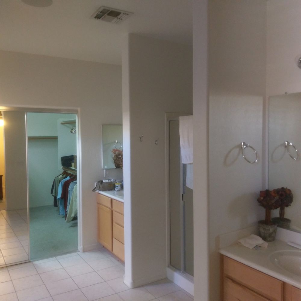 A spacious bathroom with a large mirror, double sinks, and tiled flooring.