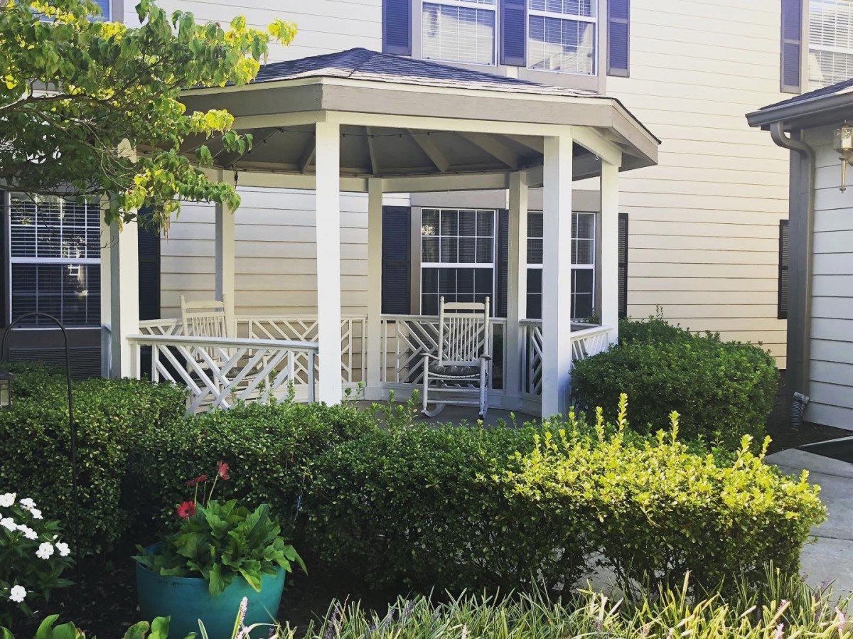 A cozy porch with a gazebo surrounded by lush greenery.
