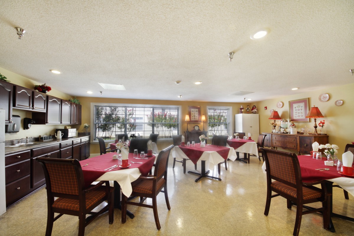 A well-lit dining area with neatly arranged tables and chairs, featuring large windows that allow natural light to fill the space.