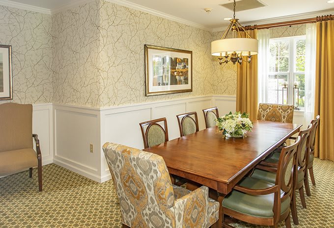 A beautifully decorated dining room featuring an elegant wooden table with chairs, ornate wallpaper, and a stylish chandelier.