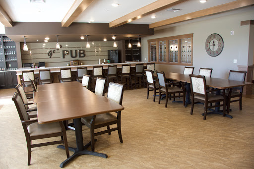 A cozy pub interior featuring wooden tables and chairs, with a welcoming bar area.