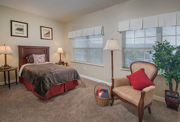 A cozy bedroom interior with a bed, chair, and lamps.