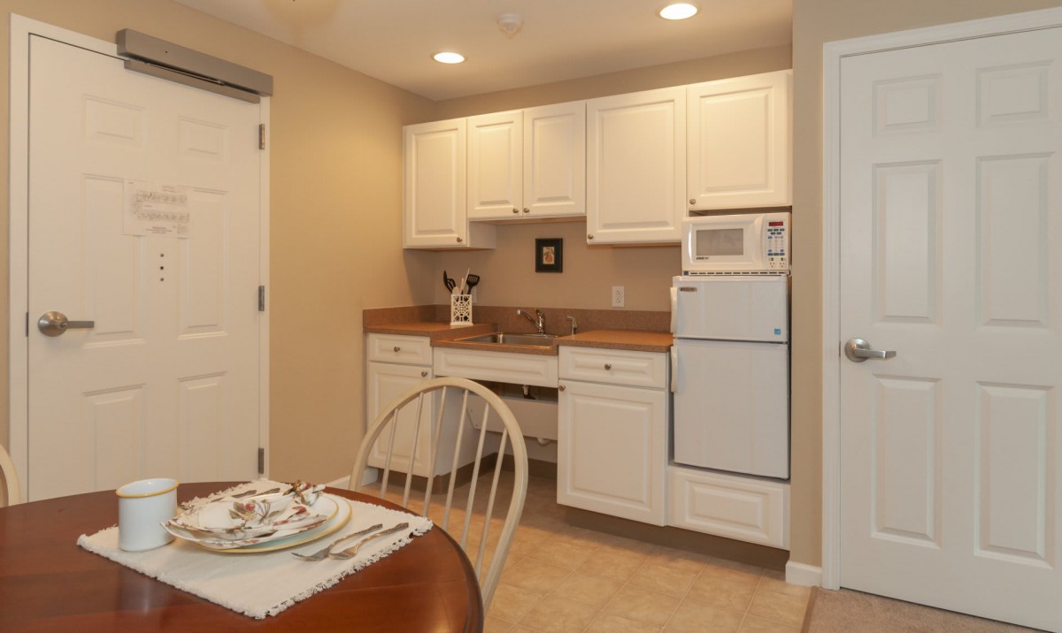 Cozy kitchen with white cabinets and a small dining area.