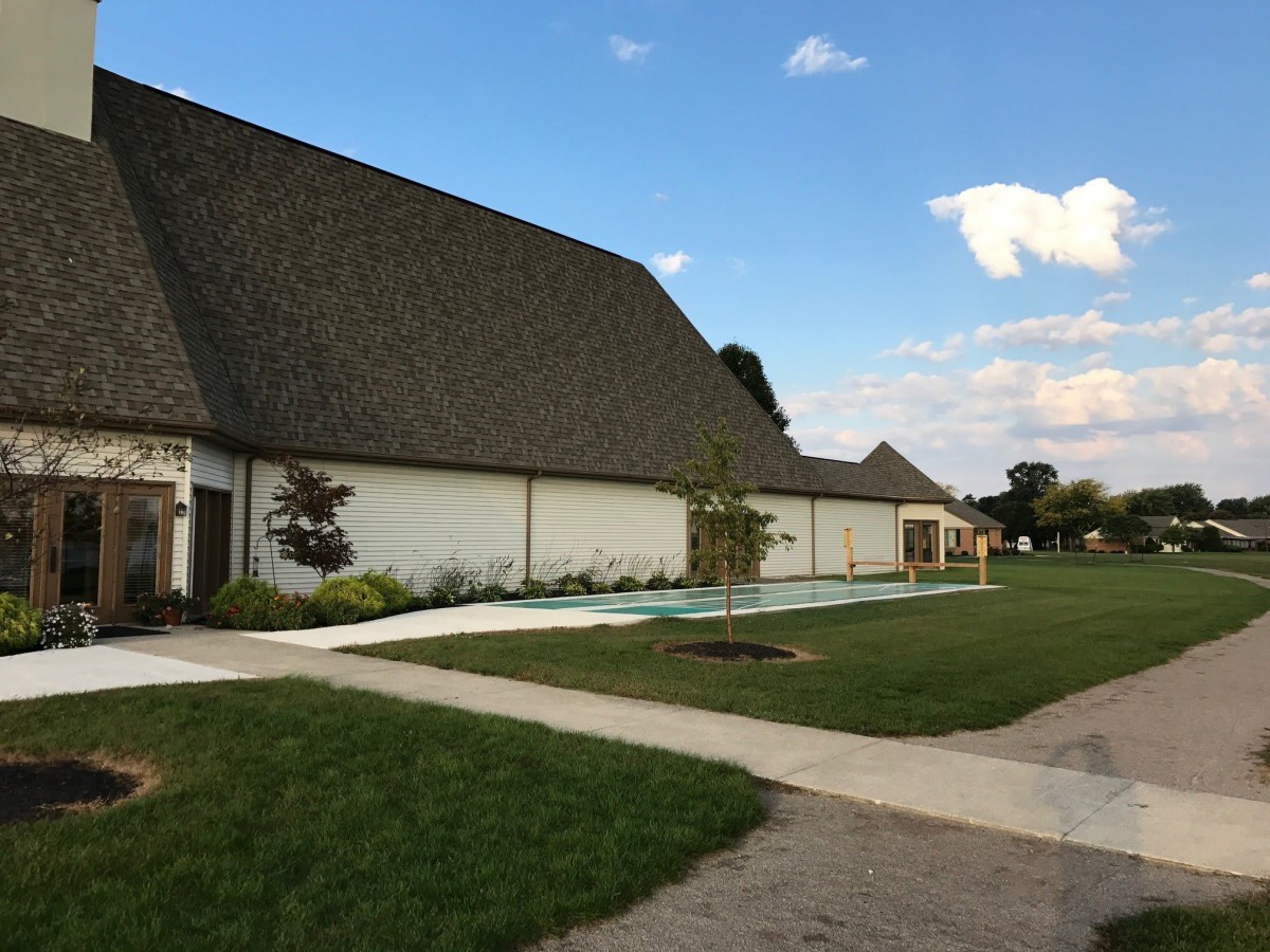 A suburban house with a well-kept lawn and sidewalk under a clear sky.