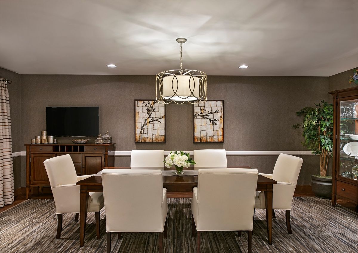 A modern dining room with a central table, upholstered chairs, and contemporary lighting.