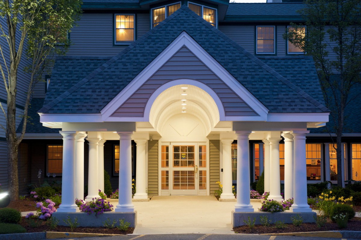 An elegant building entrance with symmetrical columns lit up in the evening.