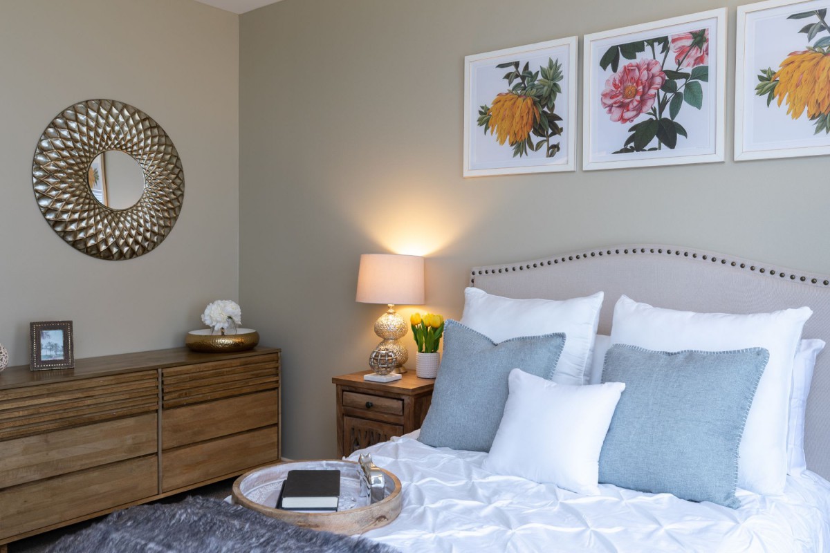 A cozy and well-decorated bedroom with a neatly made bed, pillows, and stylish artwork on the walls.