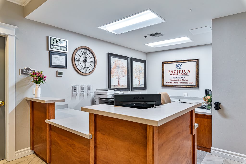 A reception desk area with a clock, office decor, and certificates on the wall.