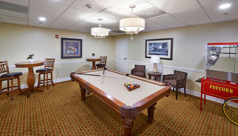A cozy billiard room featuring a pool table, comfortable seating, and elegant lighting.