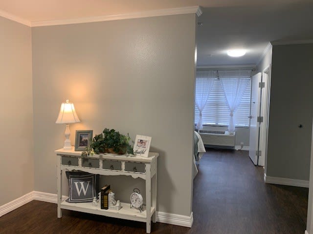 A cozy hallway featuring a decorated side table with a lamp and framed photos.