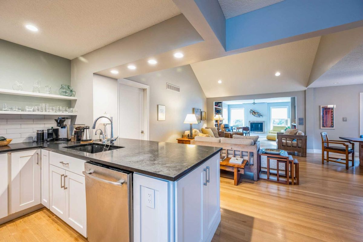 A modern open-space kitchen and living area with sleek countertops and warm wood flooring.