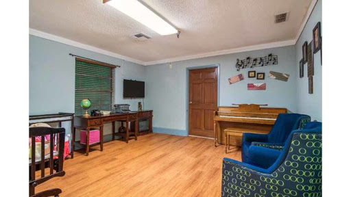 A cozy living room featuring a piano and a workspace, perfect for relaxation and creativity.