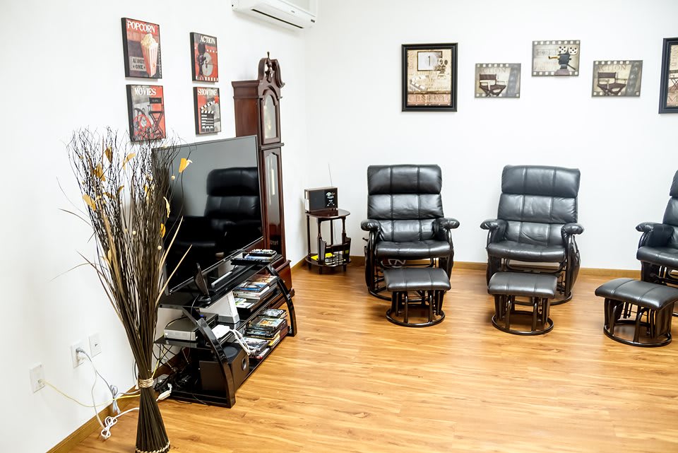 A modern living room with black leather chairs and a large television.