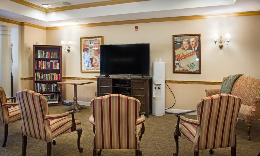 A cozy living room setup with chairs facing a television and surrounded by decorative posters.