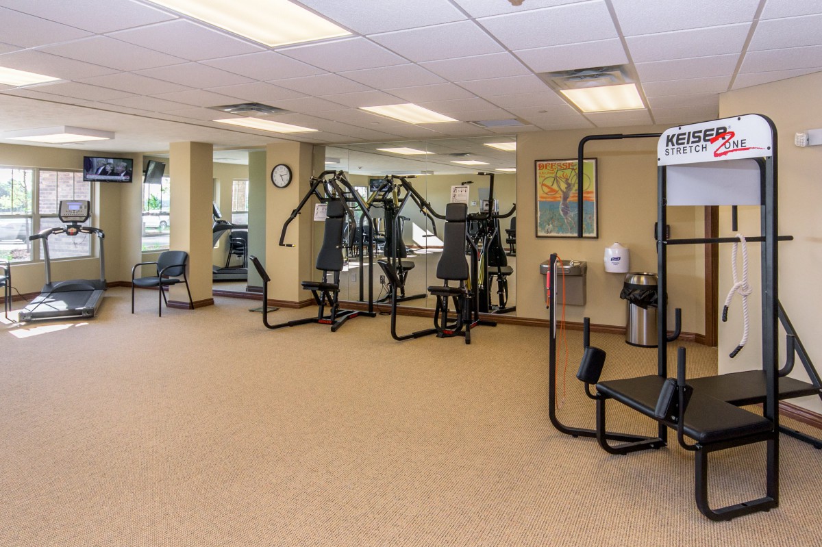 A clean and spacious gym with various exercise machines.
