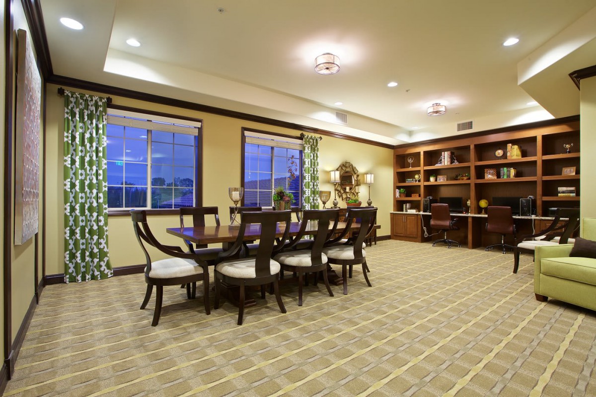 Spacious dining room with a large table, chairs, and an elegant bookshelf.
