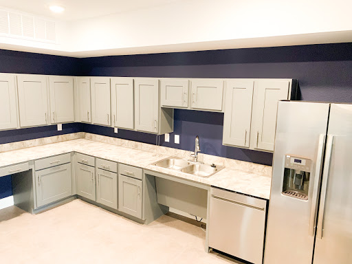 A modern kitchen featuring light grey cabinets and a deep blue accent wall, still in the process of renovation.