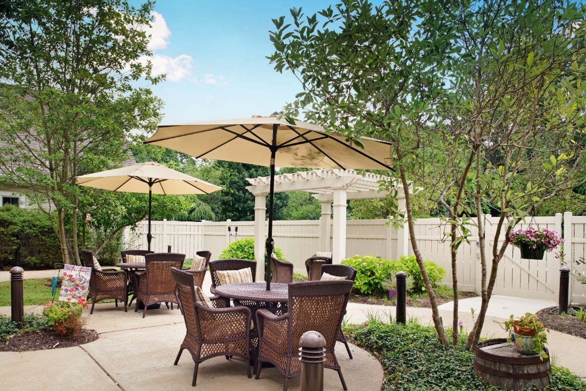 A tranquil outdoor patio area with wicker furniture and large umbrellas surrounded by greenery.