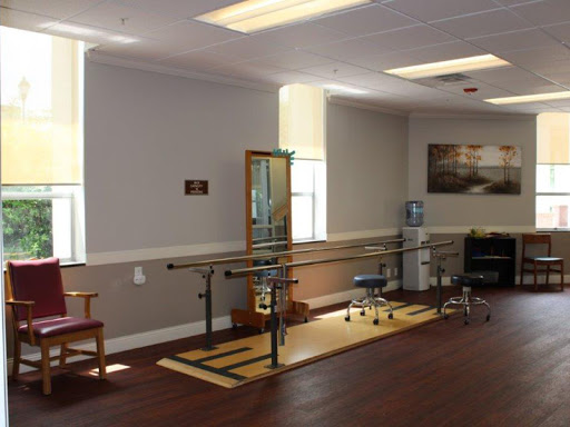 A well-equipped physical therapy room featuring parallel bars and seating.